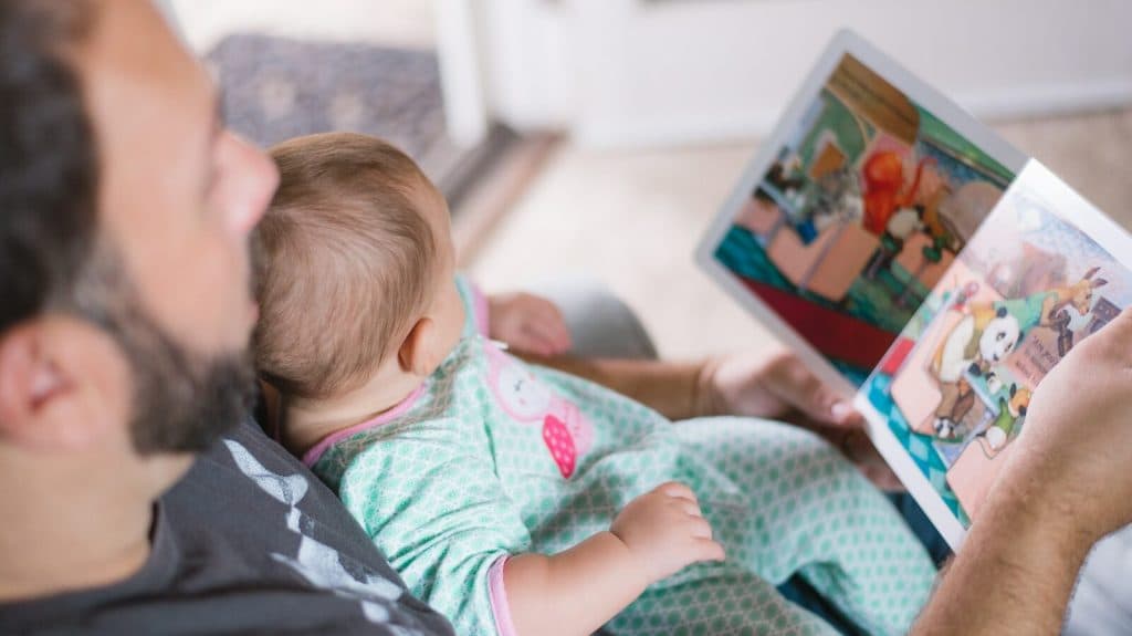 person carrying baby while reading book