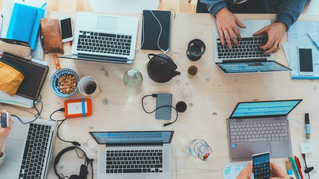people sitting down near table with assorted laptop computers